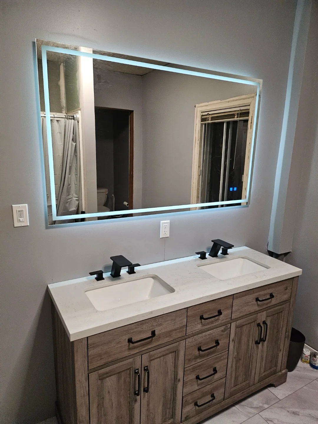 Finished bathroom vanity with an illuminated mirror and electrical controls